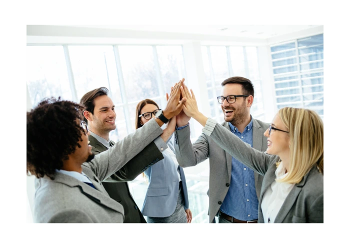 A group of employees is rejoicing, high-fiving one another
