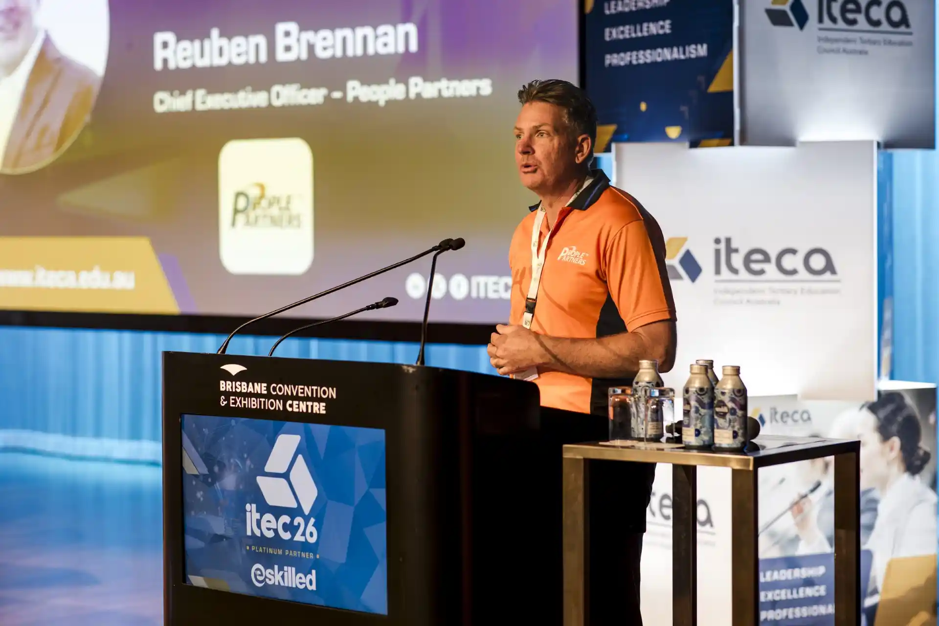 Reuben Brennan on stage giving a presentation at the ITECA Conference